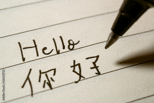 Beginner Chinese language learner writing Hello word in Chinese characters macro shot photo