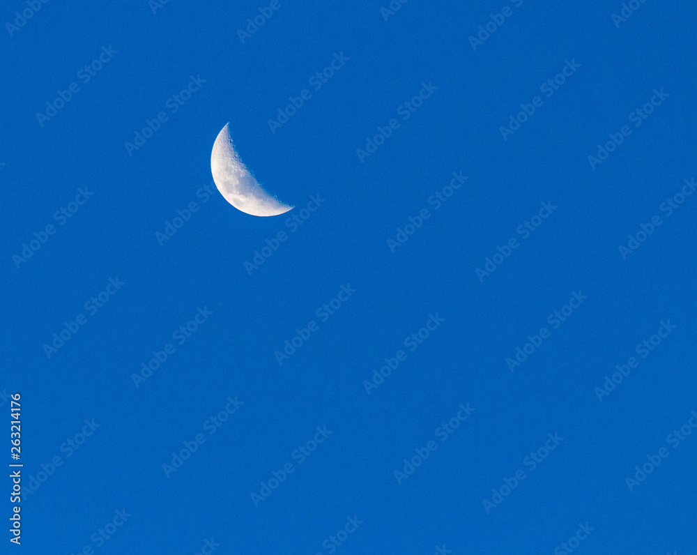 The moon during the day against a clear blue sky. The moon during the day against a clear blue sky.