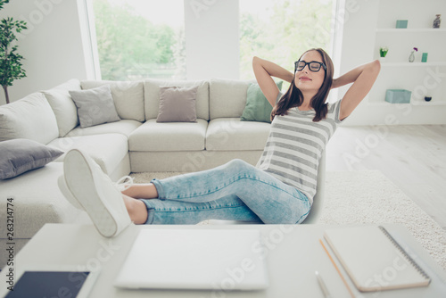 Close up photo beautiful she her lady hold hands arms behind head eyewear eyeglasses specs eyes closed wear jeans denim striped t-shirt sit comfort chair legs table house bright living room indoors