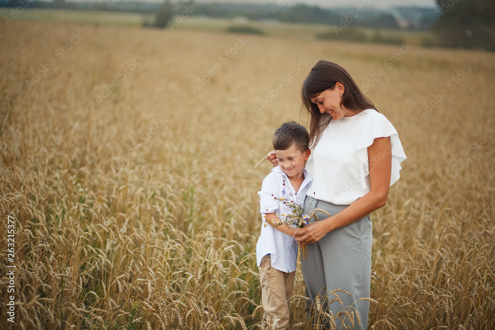 mother with son smiling holding hands and embracing in a field in summer. The concept of maternal love and tenderness, the relationship between parents and children