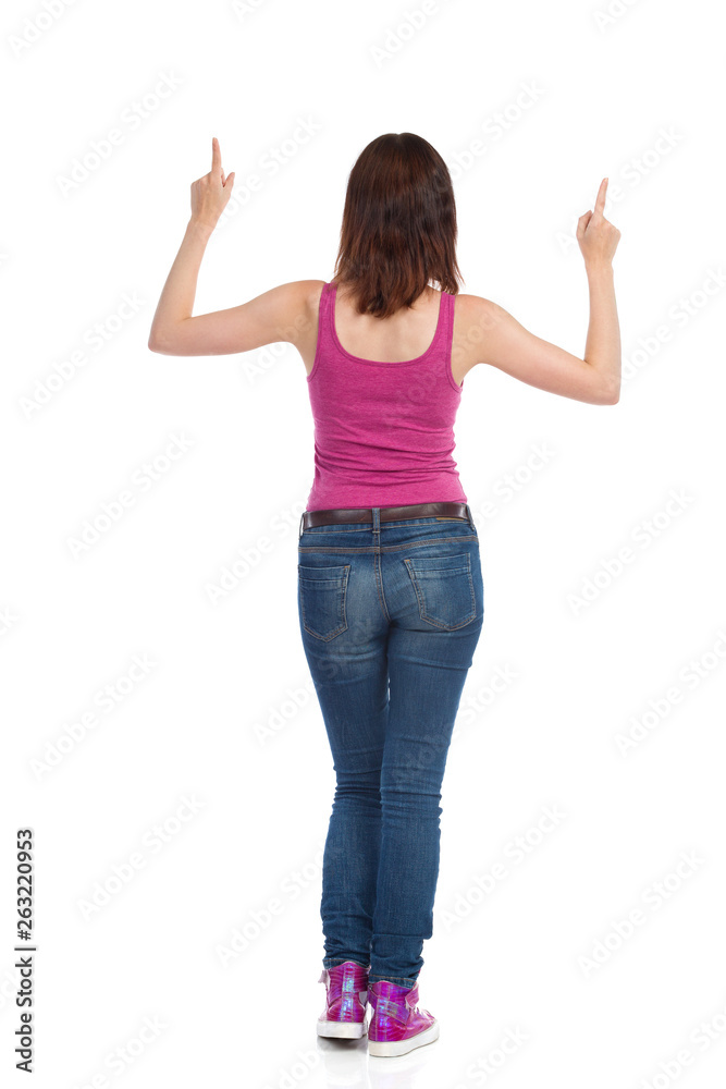 Young Woman Is Standing With Arms Raised And Pointing Up. Rear View. Young Woman Is Standing With Arms Raised And Pointing Up. Rear View.
