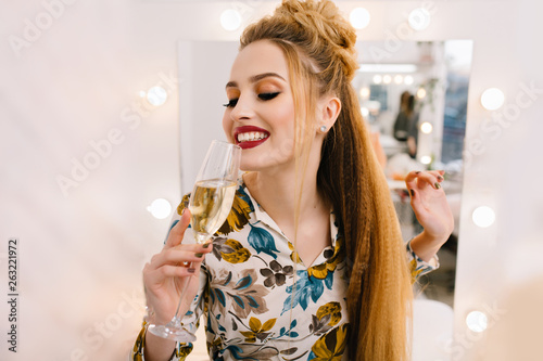 Portrait happy smiled young woman with luxury coiffure drinking glass of champagne in hairdresser salon. Expressing true positive emotions, having fun, fashionable model, joy photo