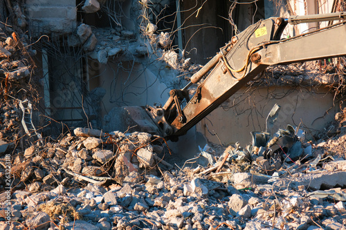 Building demolition with hydraulic excavator. Dismantle of destructed house ruins at bright sunsest © Arseny