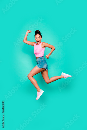 Vertical full length body size photo beautiful she her stylish trendy hairdo jump high win winner victory achievement wear casual pink tank-top jeans denim shorts isolated teal turquoise background