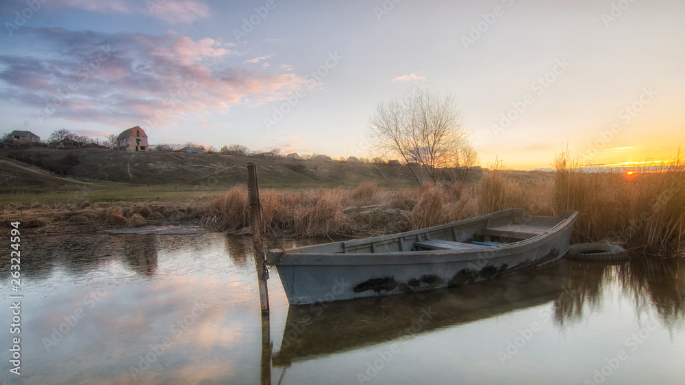 Fisherman's boat near the shore of a calm river Southern Bug, Ukraine. Sunrise. In the blue sky clouds. Panoramic view.