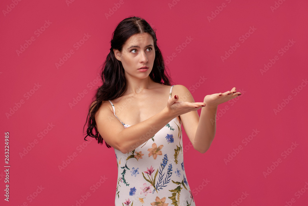Portrait of a pretty young woman in a light dress standing on pink background in studio. People sincere emotions. Portrait of a pretty young woman in a light dress standing on pink background in studio. People sincere emotions.