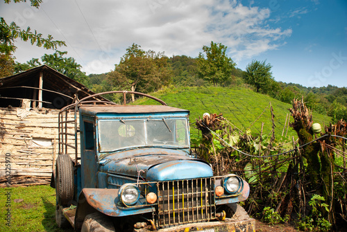 A blue old wrecked truck left alone in a green natural village