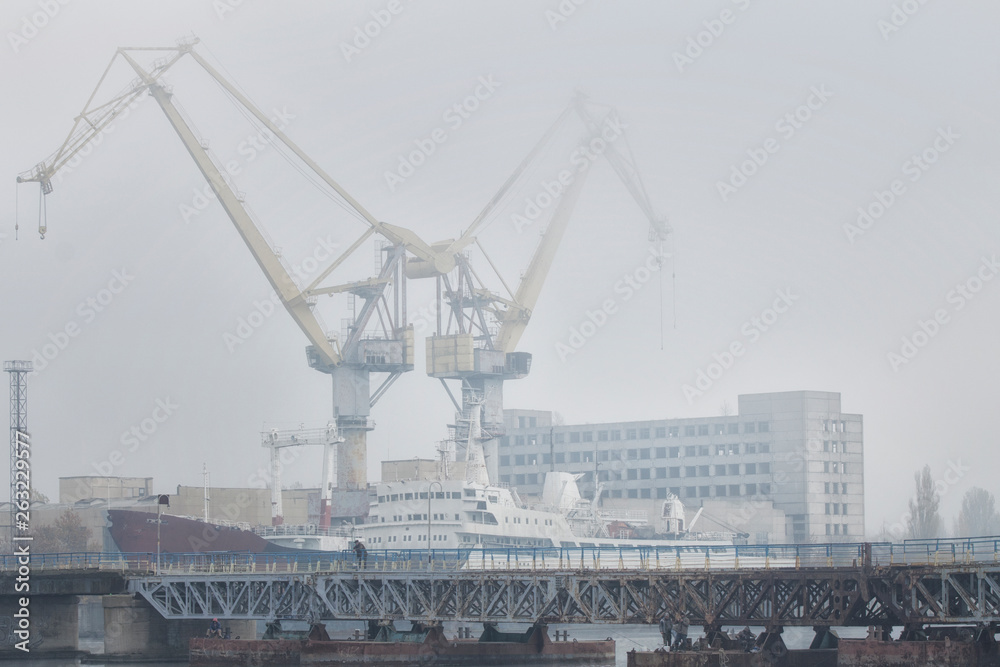 Lifting cargo cranes and ship in sea port. Foggy industrial landscape. Lifting cargo cranes and ship in sea port. Foggy industrial landscape.