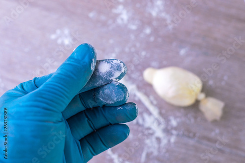 cocaine, heroin: a powdered narcotic drug on the tip of a finger of a medical expert, on a light background.