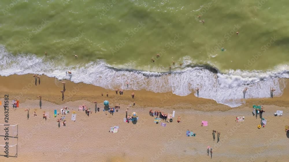 Aerial view of the beach filled with people on a hot sunny day. People swim and rest on sea ocean. 4K video. Aerial view of the beach filled with people on a hot sunny day. People swim and rest on sea ocean. 4K video.