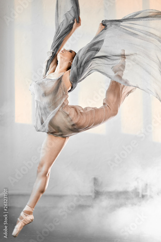 Fototapeta Naklejka Na Ścianę i Meble -  Adorable dar-haired female dancer performing on scene her part of concert jumping high in the air expressing emotions and beauty of classical ballet. Concert performance dance.
