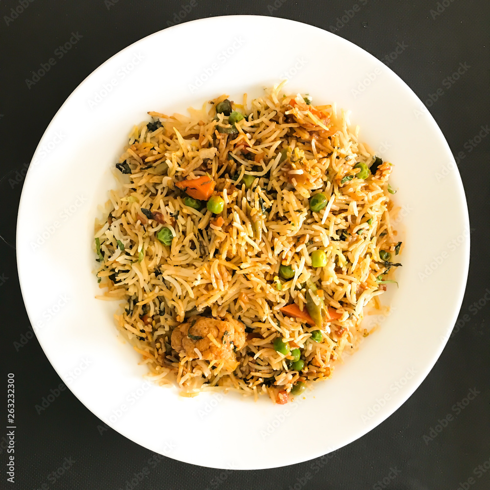 Delicious spicy biryani in white bowl on dark moody background, Popular Indian or Pakistani food Delicious spicy biryani in white bowl on dark moody background, Popular Indian or Pakistani food