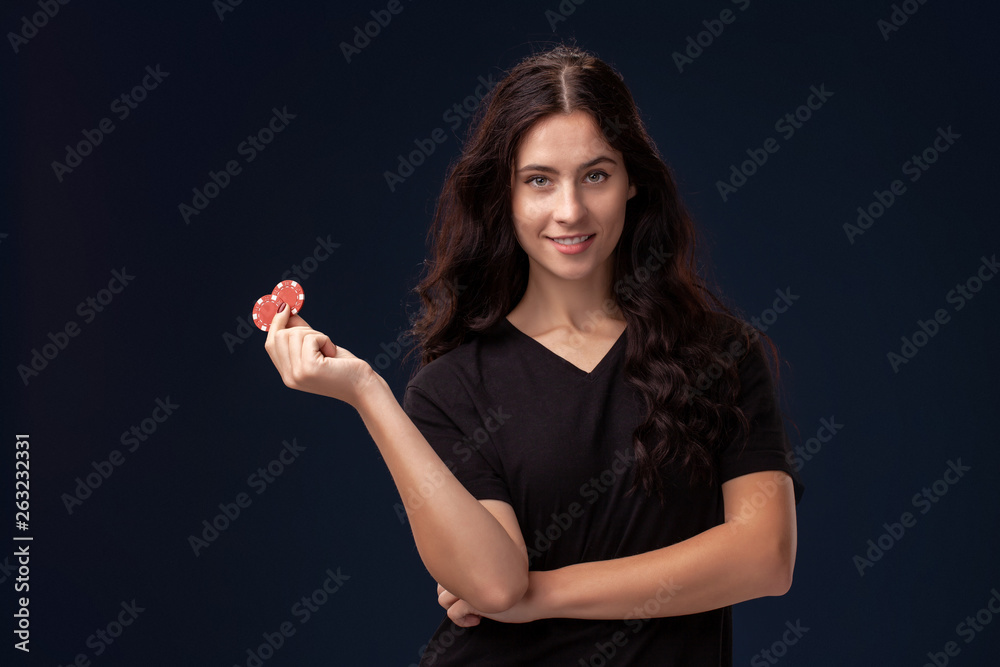 Curly hair brunette is posing with red gambling chips in her hands. Poker concept on a black background. Casino. Curly hair brunette is posing with red gambling chips in her hands. Poker concept on a black background. Casino.