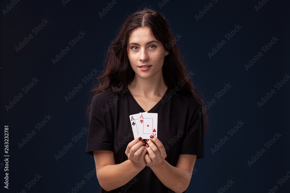 Curly hair brunette is posing with playing cards in her hands. Poker concept on a black background. Casino. Curly hair brunette is posing with playing cards in her hands. Poker concept on a black background. Casino.