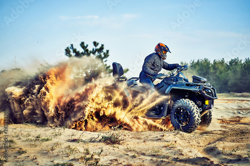 Teen riding ATV in sand dunes making a turn in the sand