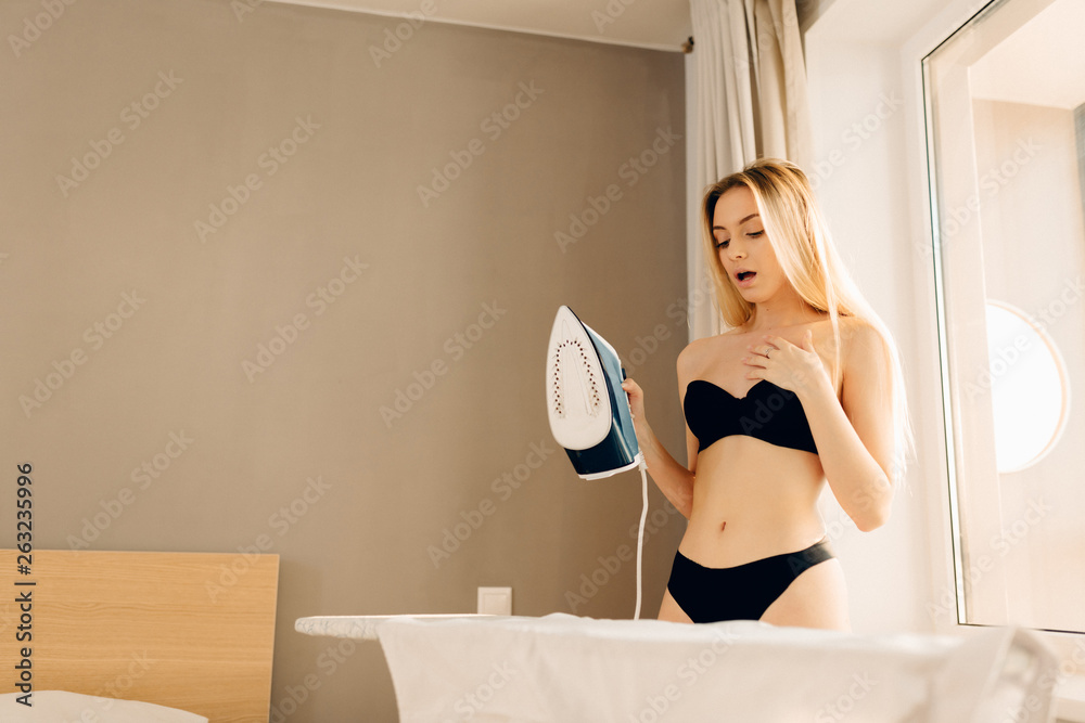 sexy blonde undressed maid ironing clothes in sunny morning at home. Woman  dressed in black bra and panties. Stock Photo | Adobe Stock