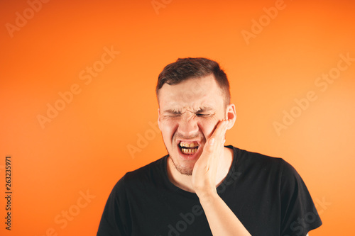 Man getting slapped on orange background Unhappy scared man getting slapped standing on orange background