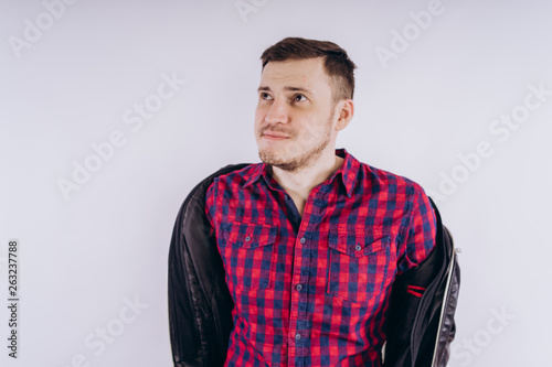 Cool man with jacket on shoulder Portrait of young handsome male in red plaid shirt holding leather jacket on shoulder against white background