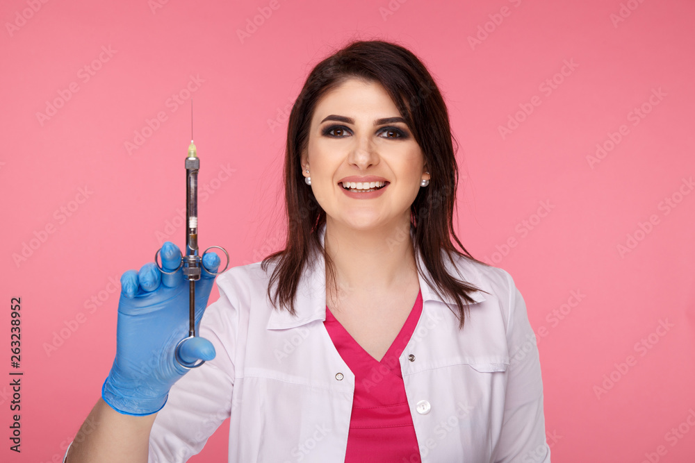 Pretty yong dentist in blue gloves with medical tool isolated over the pink background Pretty yong dentist in blue gloves with medical tool isolated over the pink background