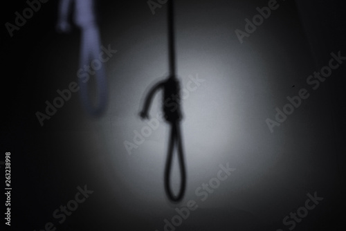 blurred shadow of the loop of the gallows on the light wall, darkness, reduced color