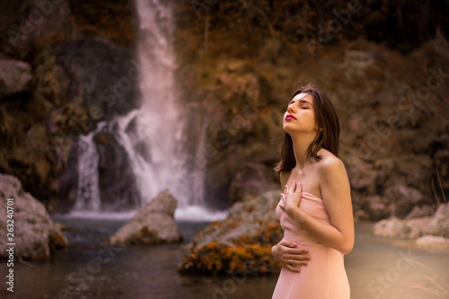 Attractive girl posing on the rock among in fairy fast forest in autumn and beside beautiful waterfall with blue water. Fairy tale. © Sergio Barceló