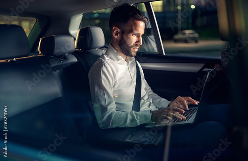 Businessman working late in car on laptop. © luckybusiness