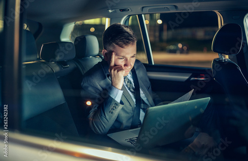 businessman in moving car working on his laptop. © luckybusiness