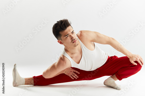 Asian man gymnastic in red sports sweatpants warming up isolated studio on white background