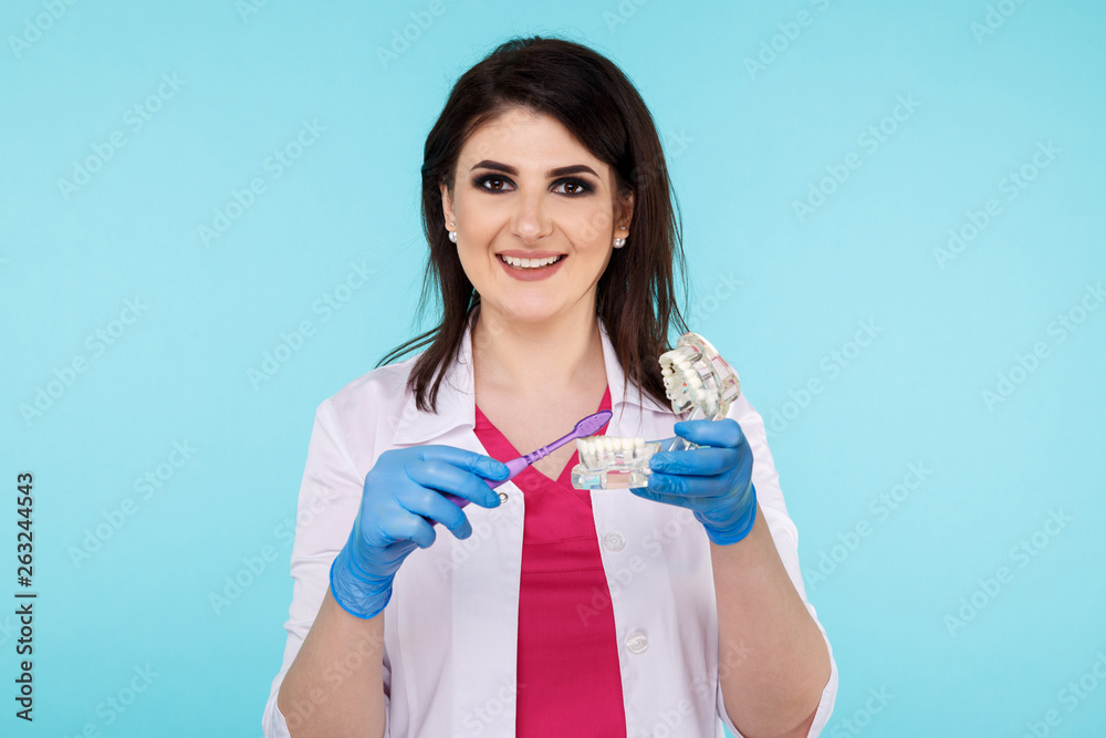 Woman dentist posing with dental tools isolated over the blue background Woman dentist posing with dental tools isolated over the blue background