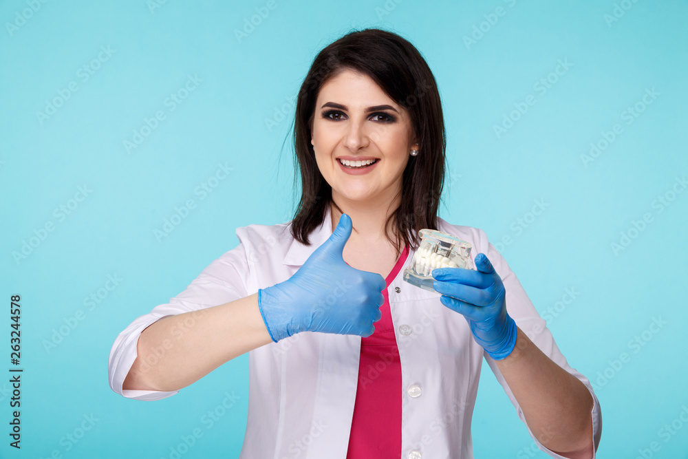 Female dentist posing with model tooth isolated over the blue background Female dentist posing with model tooth isolated over the blue background