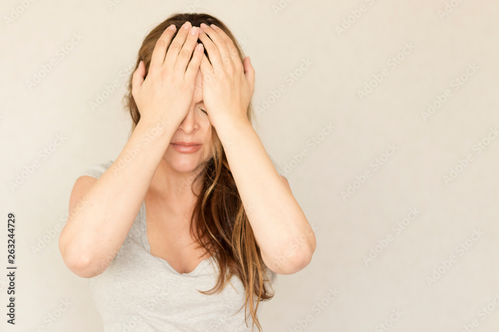 Emotions. Young woman wis headache on a gray background. Copy space. Sorry, upset girl - obrazy, fototapety, plakaty 