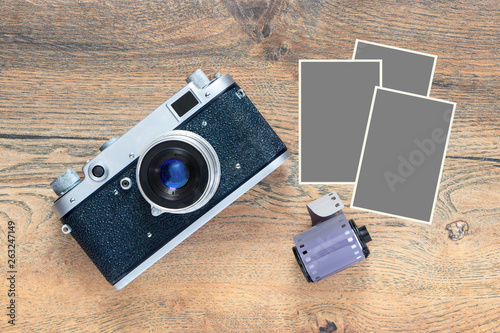 Retro film camera and cassette with footage on a wooden table background with isolated three empty frames