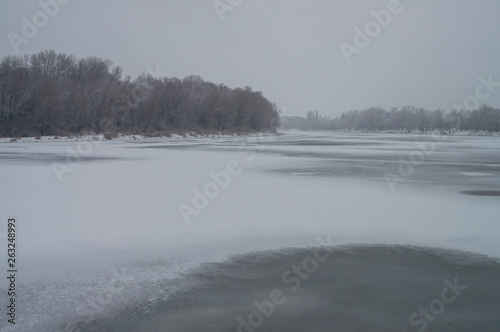Winter day. River frozen - covered with ice and naked trees covered with white snow on there branches. Walking on nature © Oksana