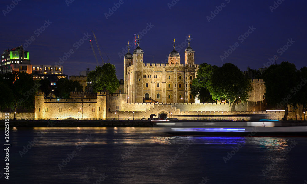 The Tower of London, an old castle and a museum where crown jewels are stored, seen from the River Thames at night. The famous fortress is located on the Tower Hill in the center of London, England