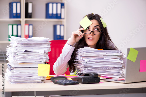 фотографія Young female employee in conflicting priorities concept