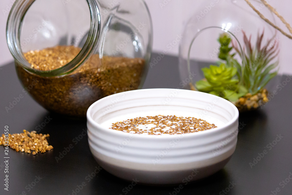 Healthy food buckwheat porridge in a plate filled with milk on a dark table with greens Healthy food buckwheat porridge in a plate filled with milk on a dark table with greens