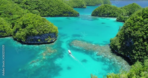 Boat travels through tropical lagoon and islands in Palau, Micronesia photo