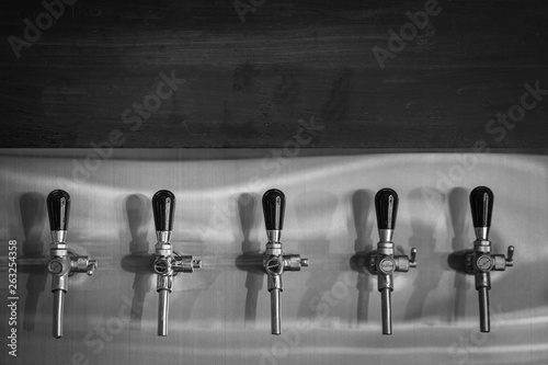 Draft beer tap faucet row in beverage bar.
