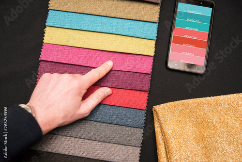 A man chooses in a store where furniture for a sofa fabric is sold, by way of example of color choices. System of color selection for fabrics on sofa