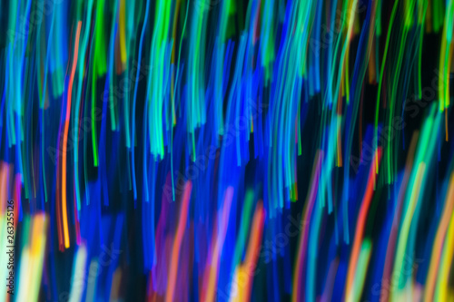Blurry abstract background with wavy multicolor lines. Neon lights in motion. Defocused lens flare glow.