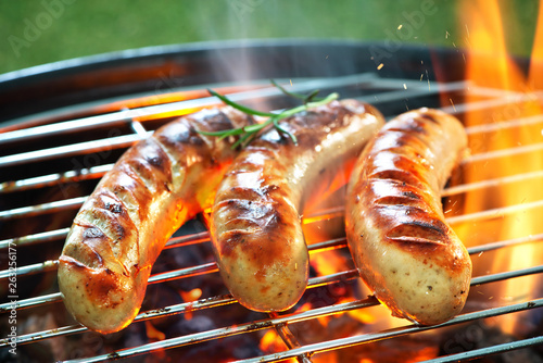 Delicious sausages sizzling over the coals on barbecue grill photo