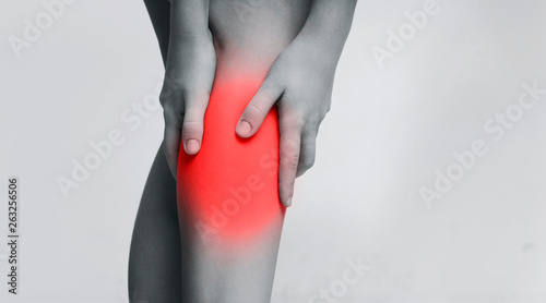 Young woman suffering from pain in leg, massaging inflamed zone