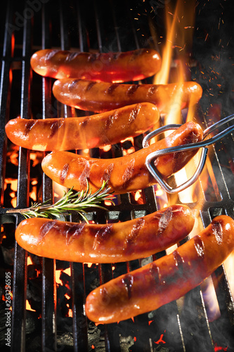 Fotografie Delicious sausages sizzling over the coals on barbecue grill