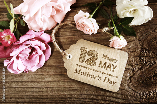 Mothers Day message with small pink roses on wooden table photo