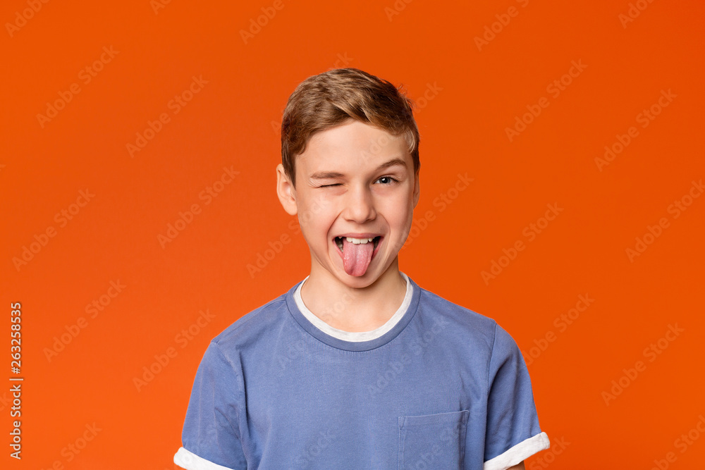 Playful teen boy winking and sticking out tongue - obrazy, fototapety, plakaty 