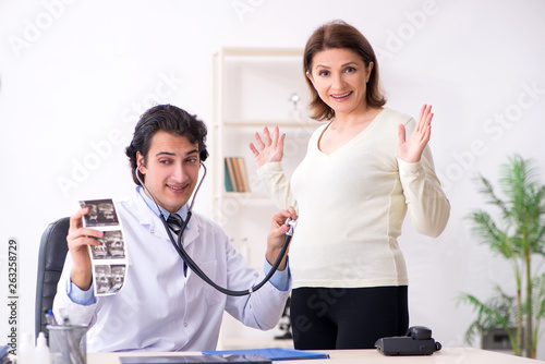 Old pregnant woman visiting young male doctor  photo