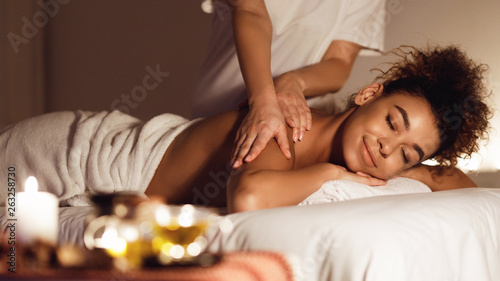 African-american girl enjoying relaxing back massage in spa photo