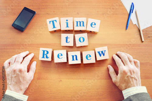 Time to renew. Businessman made text from wooden cubes on a desk