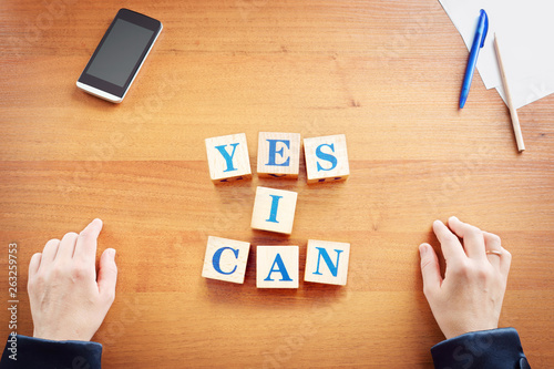 Konstfotografi Yes I Can. Business woman made text from wooden cubes on a desk