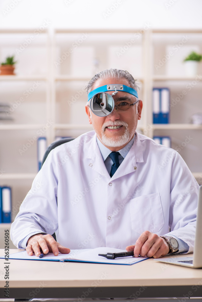 Aged male doctor laryngologist working in the clinic 